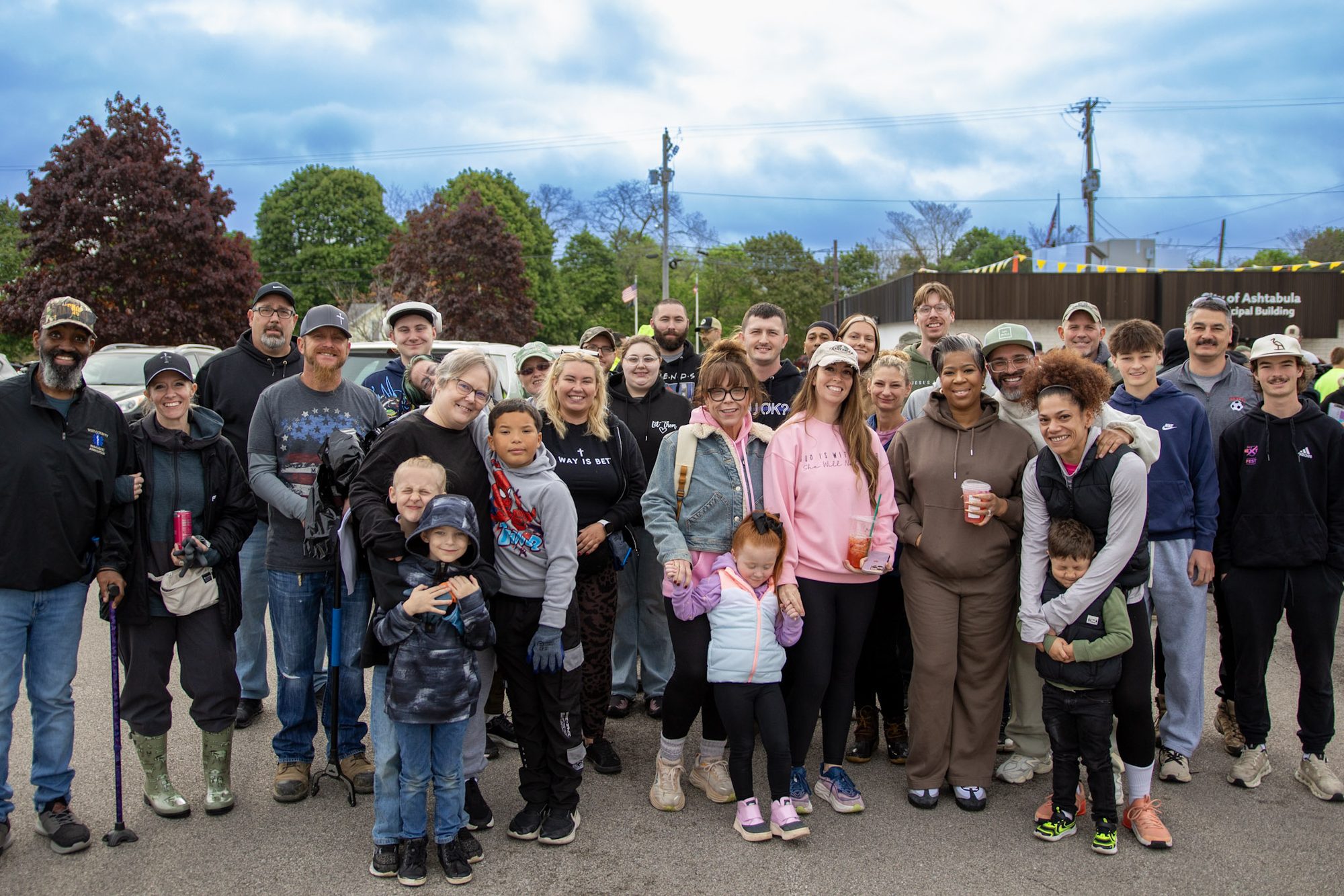 A large group of volunteers, adults and kids, gathered outside the City of Ashtabula Municipal Building