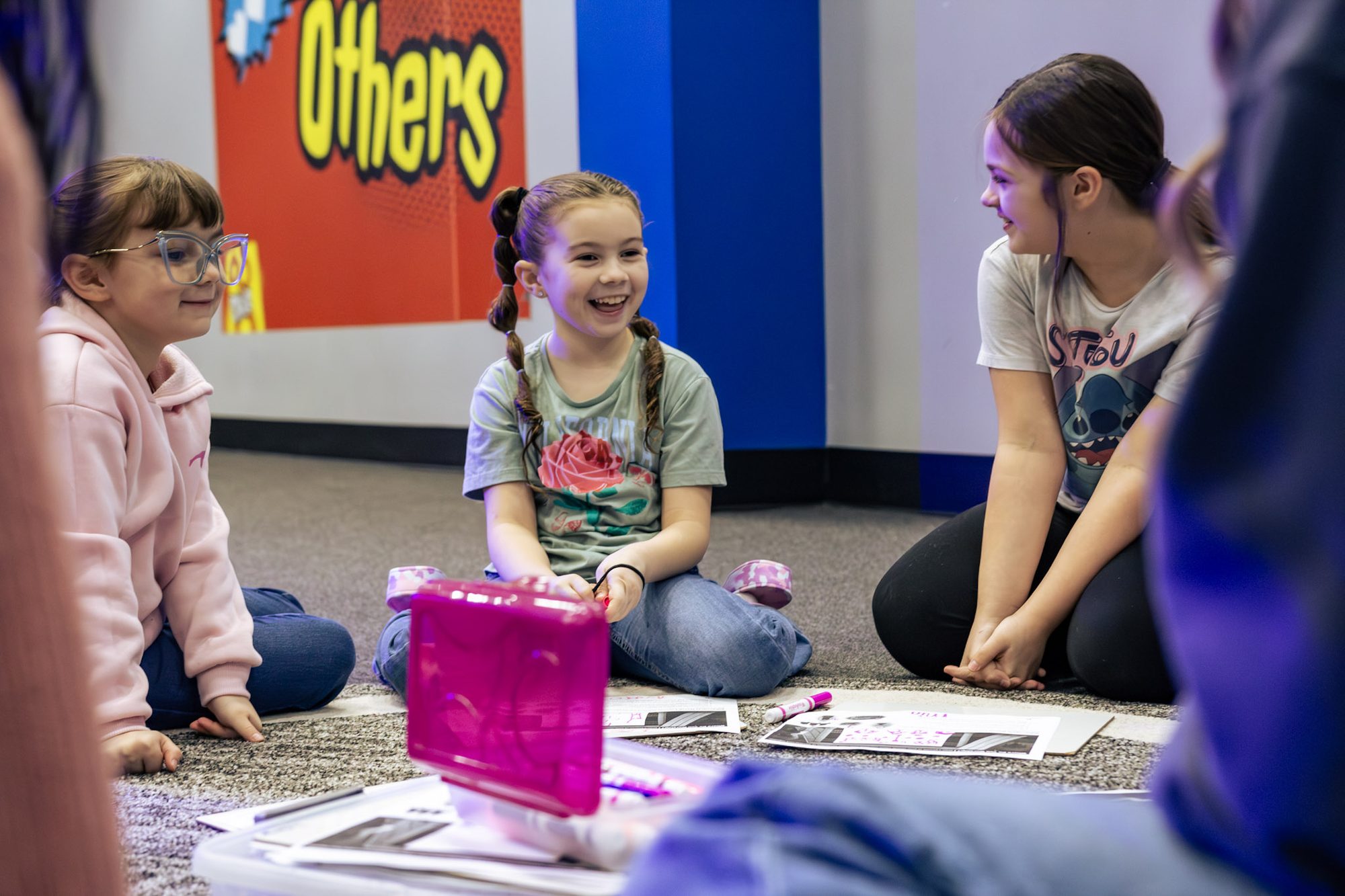 Three children sitting on the floor and laughing together in CKidz