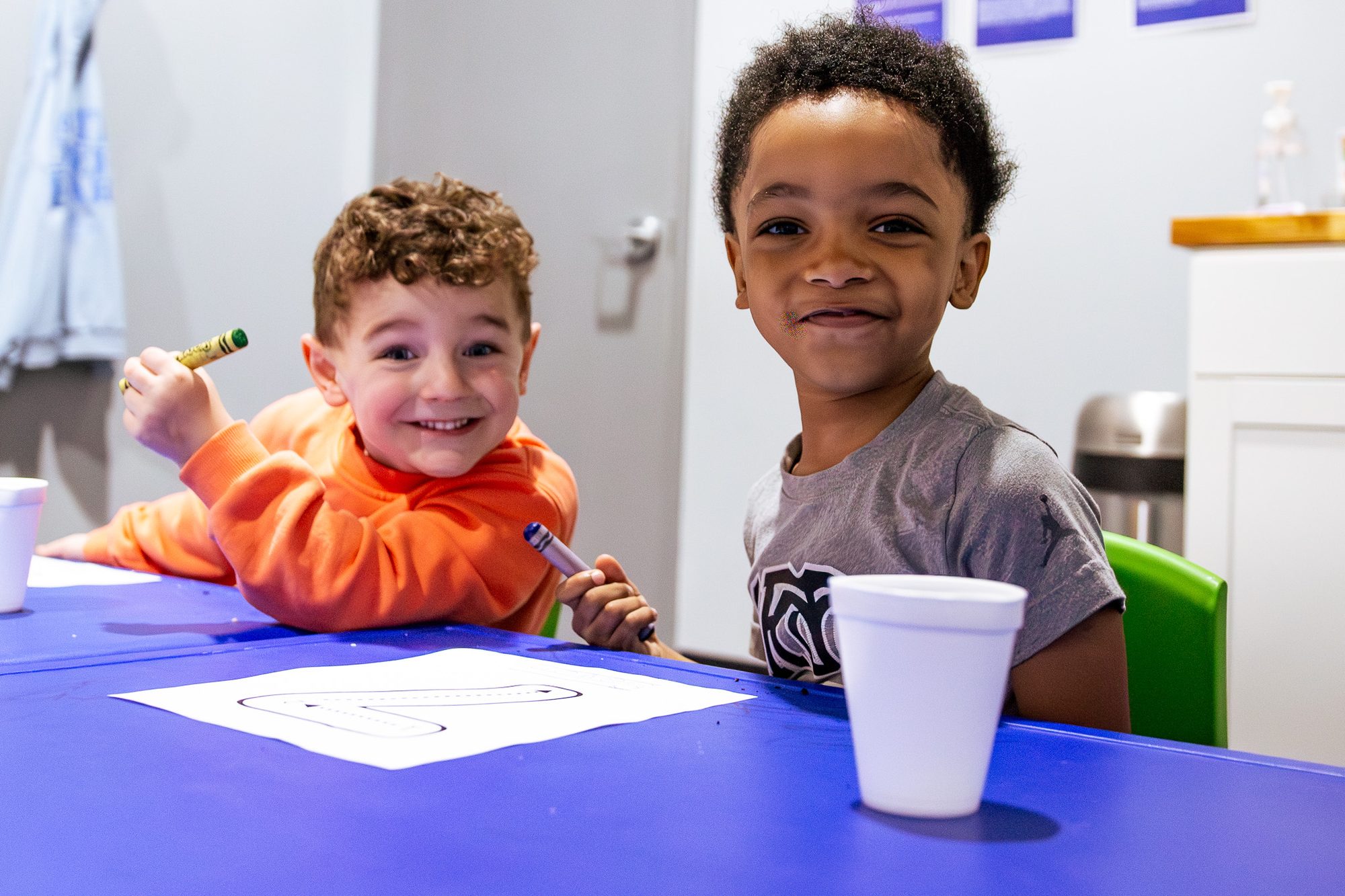 Two boys smiling and colouring at a table in CKidz