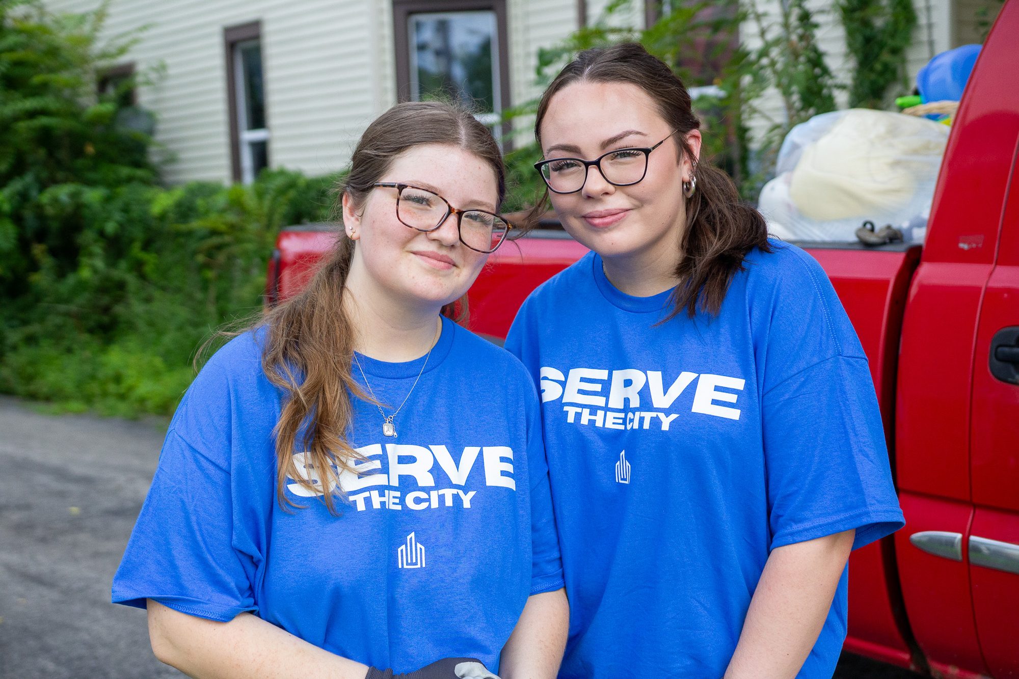 Two Serve the City volunteers in blue shirts beside a truck on Serve Day