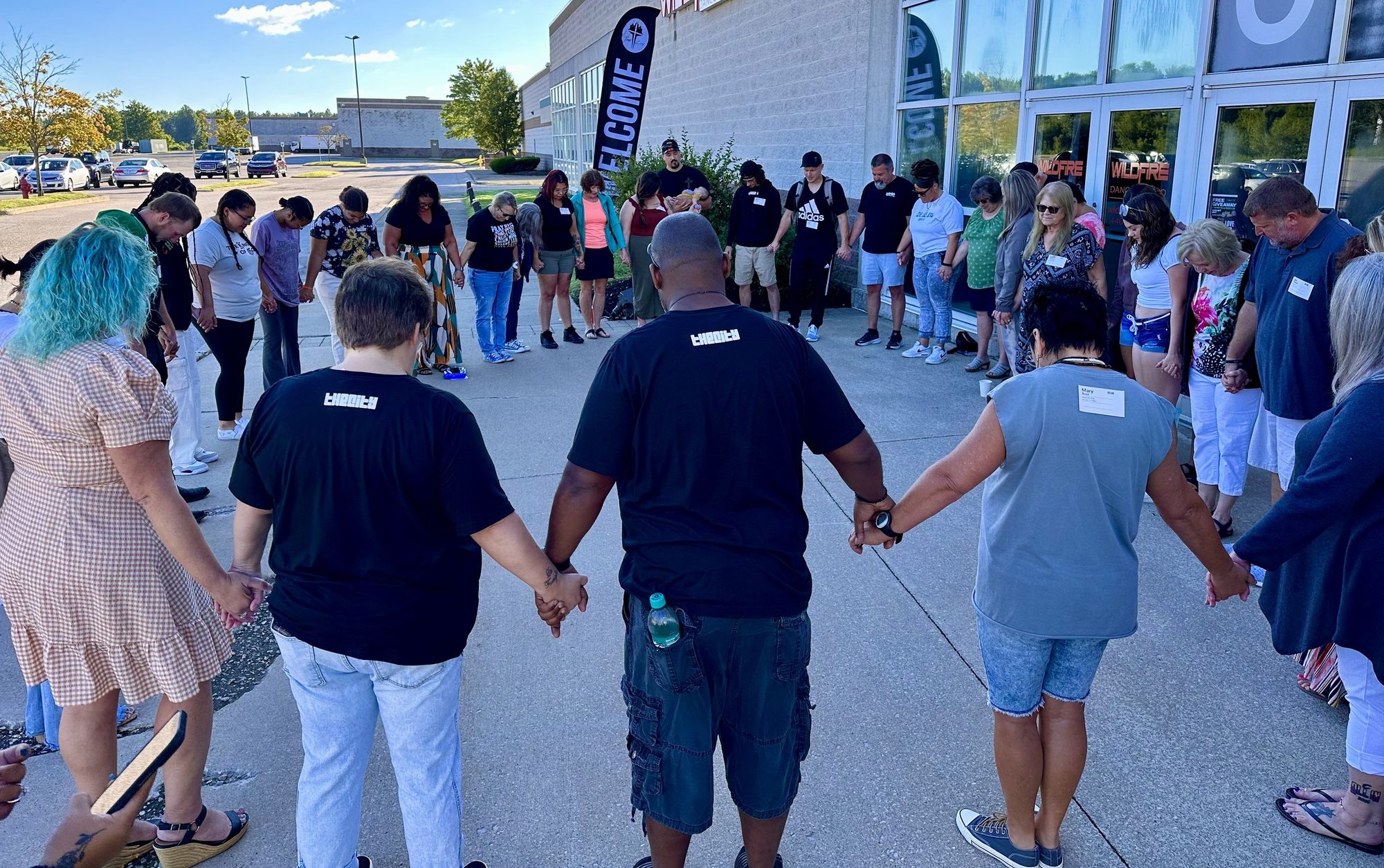 People standing in a circle outside the church, holding hands and praying